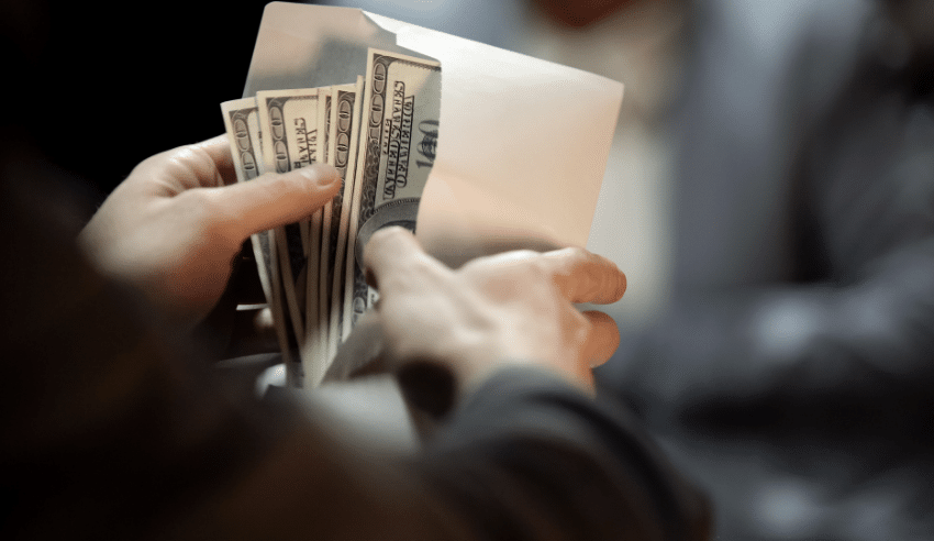 person pulling one hundred dollar biils out of an envelope
