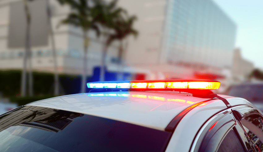 police vehicle lights on against the palm trees
